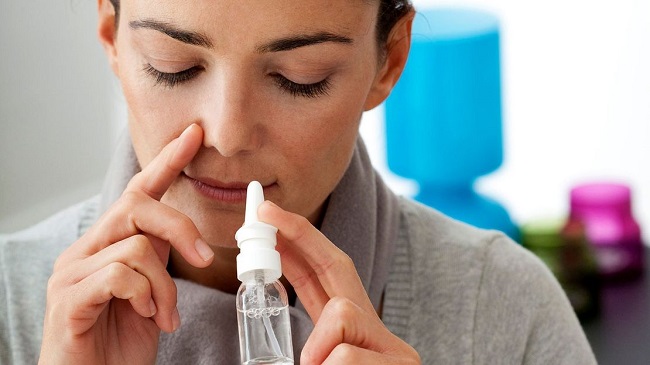 picture of a person applying a spray  in her nose