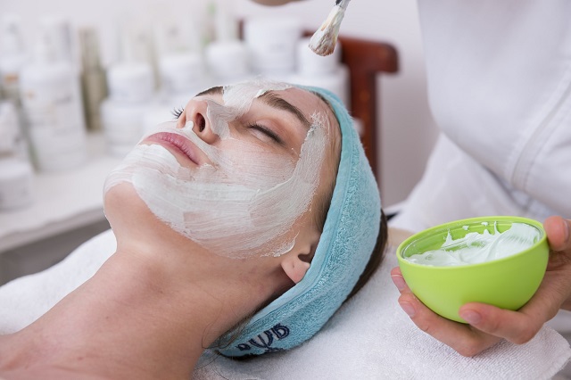 picture of a woman beside other putting a skincare mask on her face 