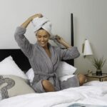 Woman in bathrobe sitting on bed