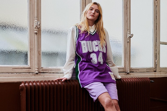 picture of a woman wearing vince carter jersey standing beside a radiator next to windows 
