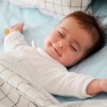picture of a happy baby sleeping on a baby manchester bedding