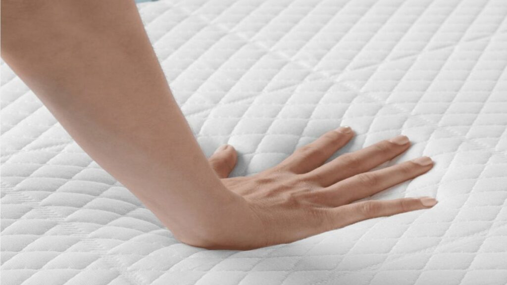 woman's hand touching memory foam mattress