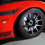 Close-up of a red sports car's wheel with Hurricane and Harrop branding.