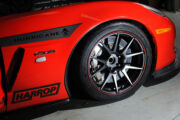 Close-up of a red sports car's wheel with Hurricane and Harrop branding.